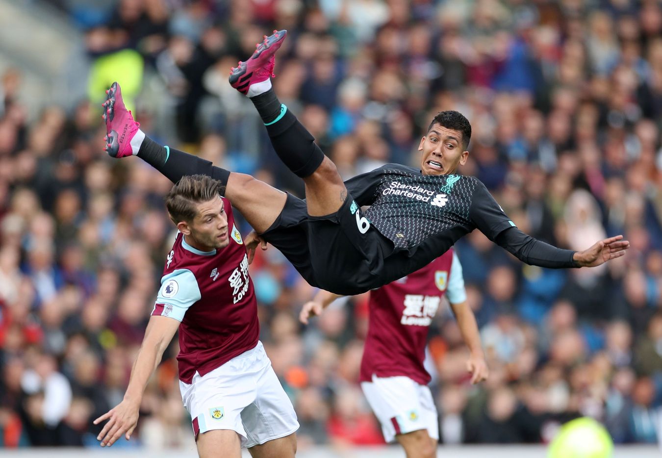 Tiền đạo Roberto Firmino bay bổng trên không trung sau pha va chạm với James Tarkowski bên phía Burnley.