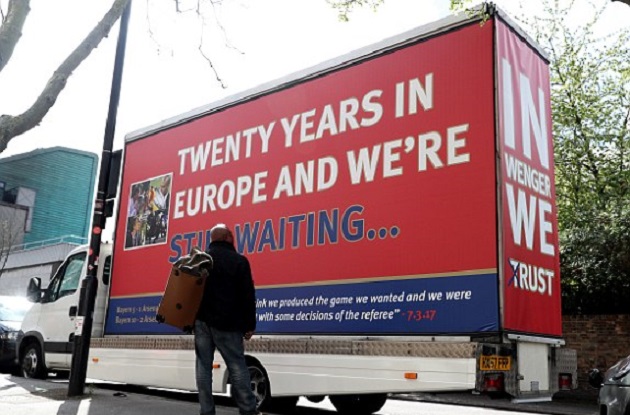 Phía sau chiếc xe tải là dòng chữ: "In Wenger we trust" với chữ "t" bị xóa.