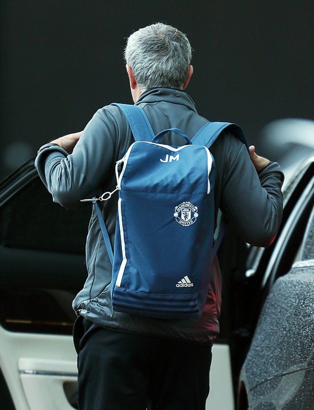 Trên vai ông là một chiếc balo màu xanh có logo của M.U.