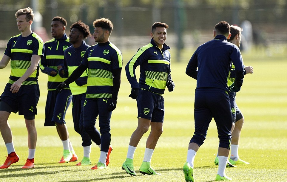 Sanchez tươi cười cùng đồng đội, trong khi những cầu thủ khác đang tập trung cho buổi tập.