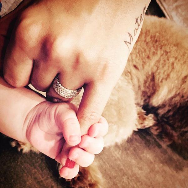 Ảnh chụp tay hai mẹ con Antonella Roccuzzo và Mateo với nền là chú chó. Ảnh: Internet.