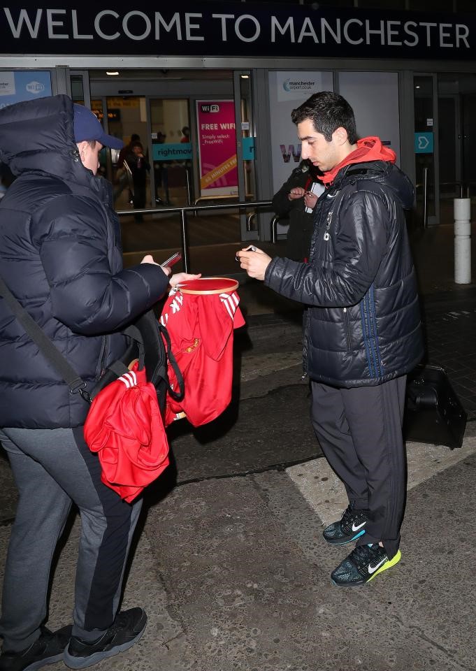 Ngôi sao Henrikh Mkhitaryan tập tễnh bước đến ký tặng cho 1 CĐV. Người này cẩn thận kéo căng chiếc áo bằng khung thêu.