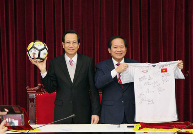 Bộ trưởng Lao động Thương binh Xã hội Đào Ngọc Dung và Bộ trưởng Thông tin Truyền thông Trương Minh Tuấn nhận quả bóng và chiếc áo đấu của U23 từ Thủ tướng Nguyễn Xuân Phúc để đấu giá.