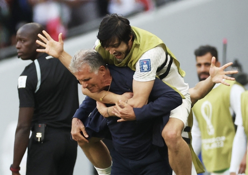 Tiền đạo Sardar Azmoun ăn mừng cùng HLV trưởng Carlos Queiroz sau trận thắng Xứ Wales.