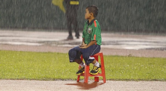 Cậu bé nhặt bóng đội mưa trên sân Gò Đậu được một CĐV chia sẻ trên facebook. Ảnh: Internet.