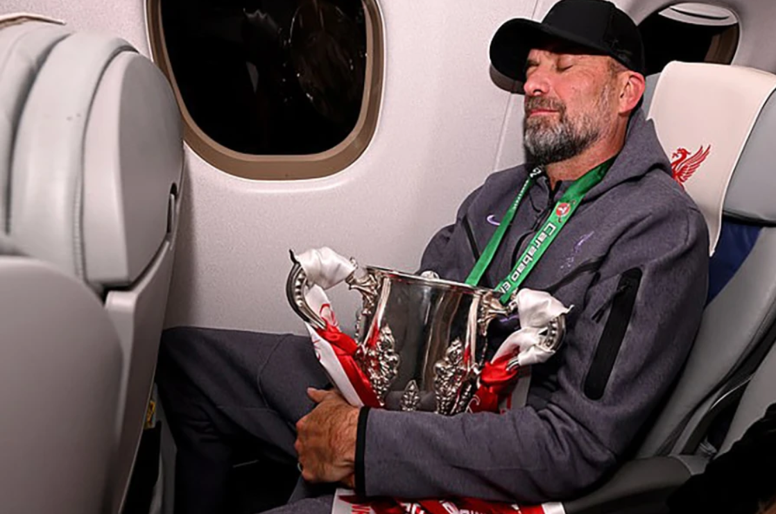Tiring business eh, Jurgen? Exhausted Klopp cradles the Carabao Cup as he sleeps on the flight back to Liverpool after his Reds side triumph - Bóng Đá
