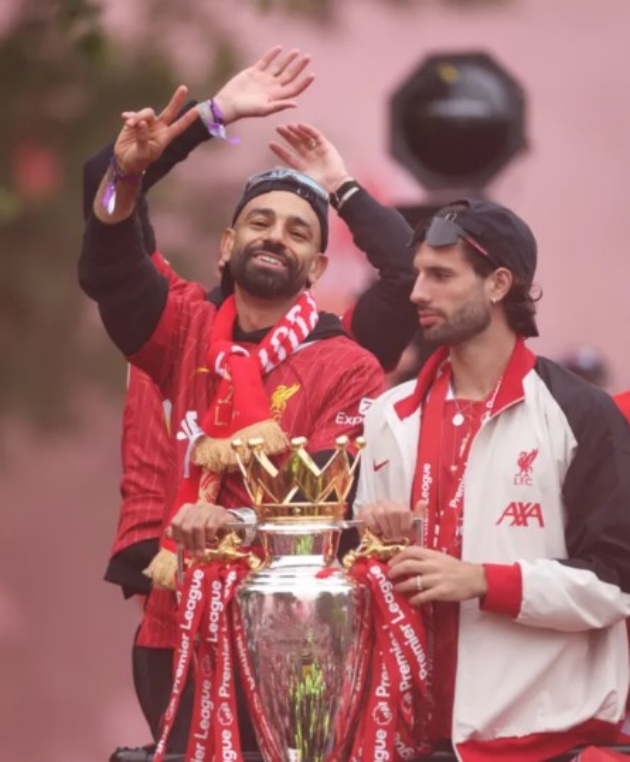 Mo Salah – Vua phá lưới và Cầu thủ xuất sắc nhất Premier League mùa này – ngồi nổi bật ở đầu xe buýt, vẫy chào đám đông người hâm mộ không ngừng hò reo. Bên cạnh Salah là Szoboszlai.