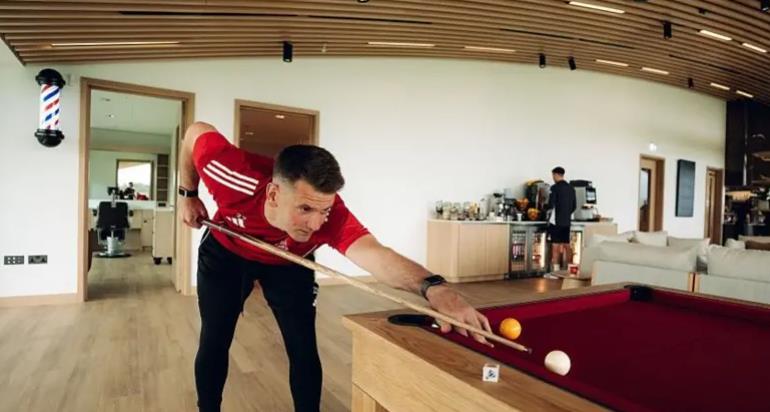 Tom Heaton chơi bi-a trước phòng cắt tóc trong khu sinh hoạt chung của đội một tại sân tập vừa được nâng cấp.